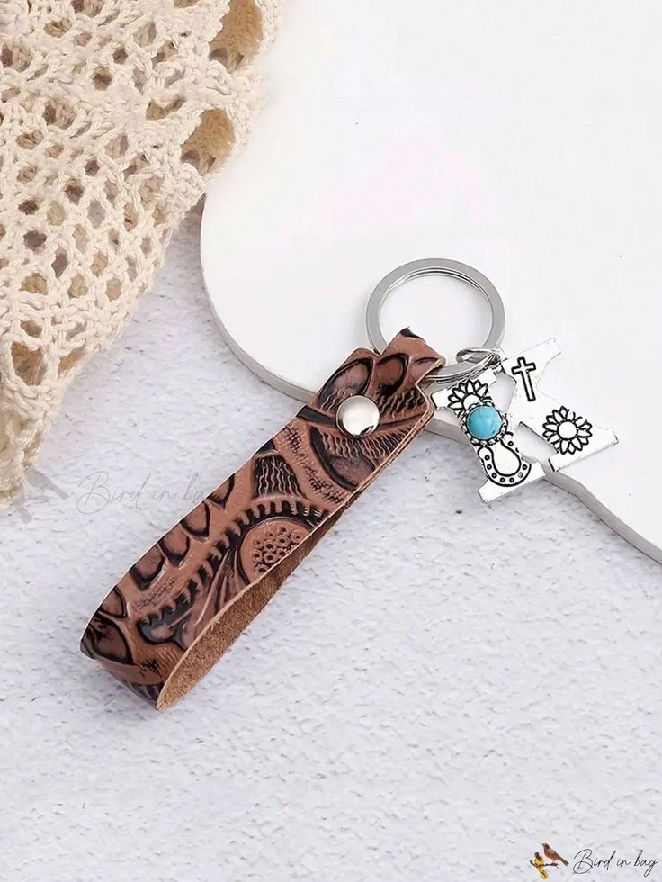 a brown leather keychain with an ornate design on it