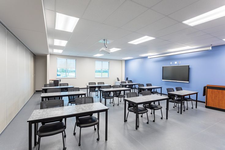 an empty classroom with desks and chairs in front of a flat screen tv on the wall