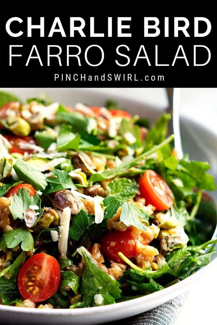 a salad with tomatoes, lettuce and other toppings in a white bowl