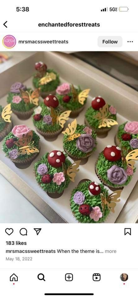 cupcakes decorated with edible flowers and leaves are displayed in a box on the table