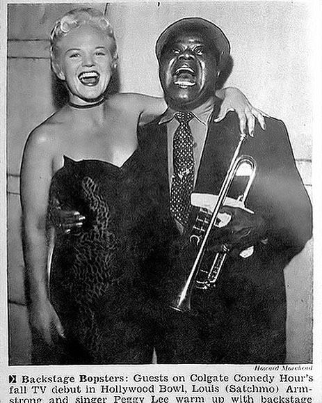 an old black and white photo of two people posing for the camera with a trumpet