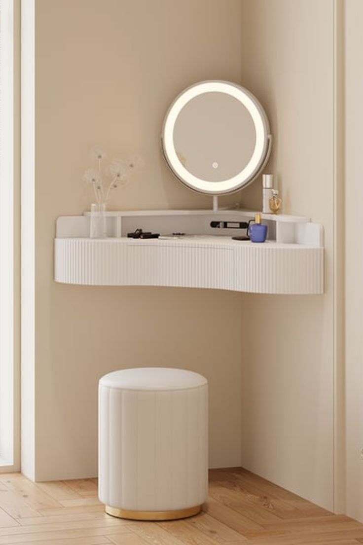 a white vanity with a round mirror above it and a stool in front of it