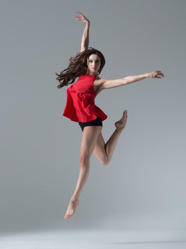 a woman is jumping in the air with her legs spread out and arms outstretched to the side