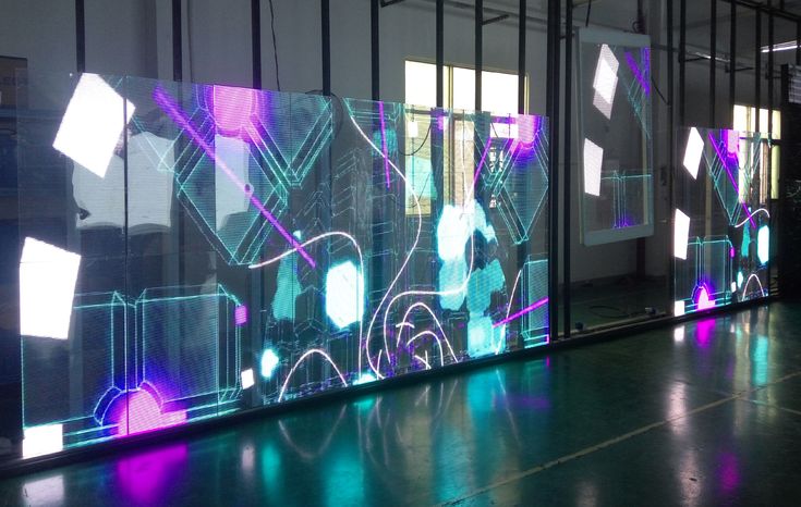 an art installation is shown in front of large glass panels with colorful lights on them