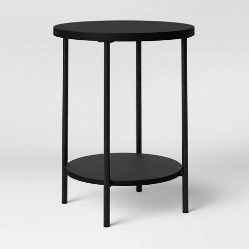 a black table with a round top and metal frame on the bottom, against a white background