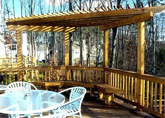 a wooden deck with white chairs and table under a pergolated roof over looking the woods