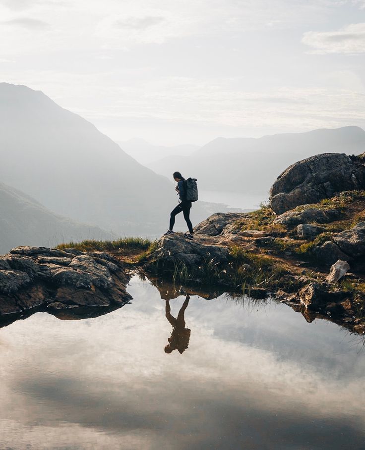 a person standing on top of a mountain next to a body of water