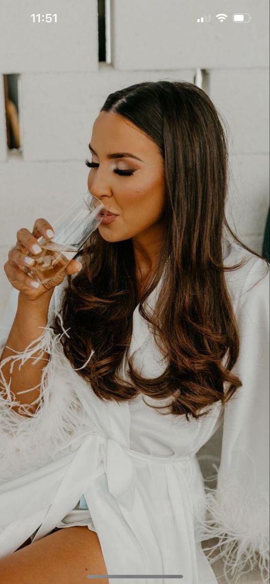 a woman sitting on the ground with her hair blowing in front of her face and wearing a white robe