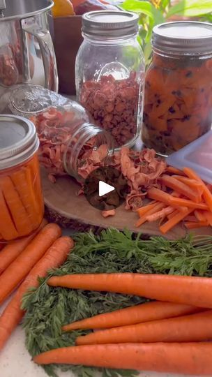 carrots and other vegetables sit on a table with jars full of food in them