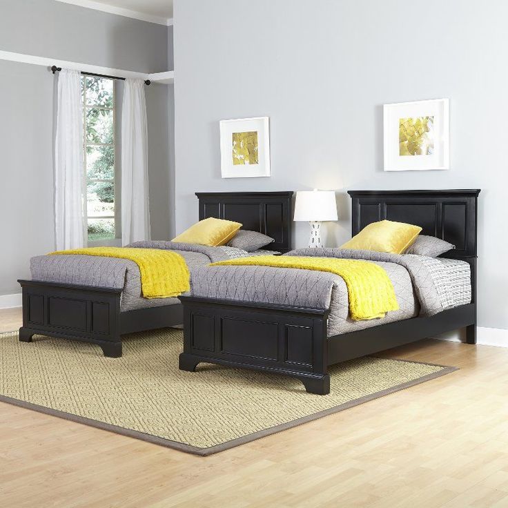 two beds in a room with hardwood floors and yellow pillows on the bedding,