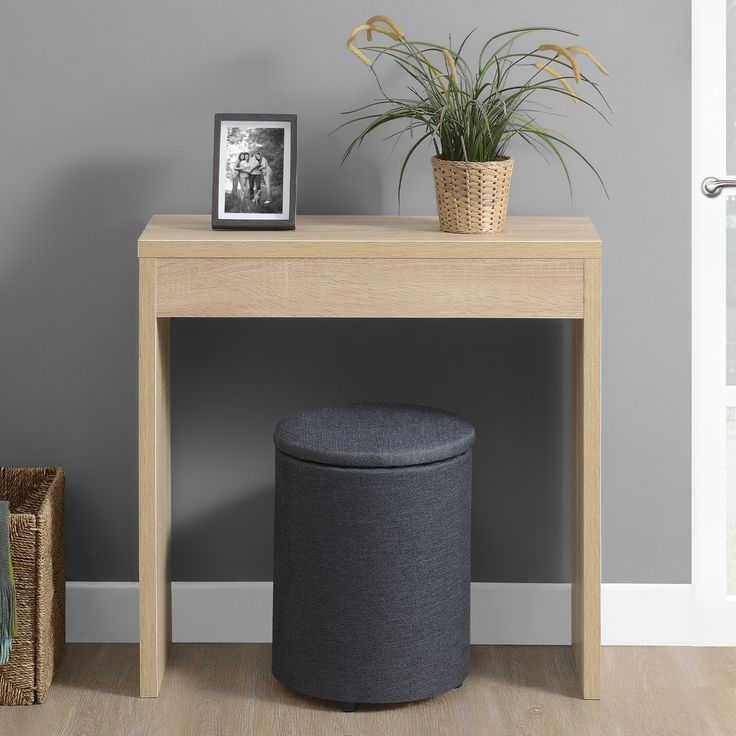 a small table with a potted plant next to it and a round ottoman on the floor