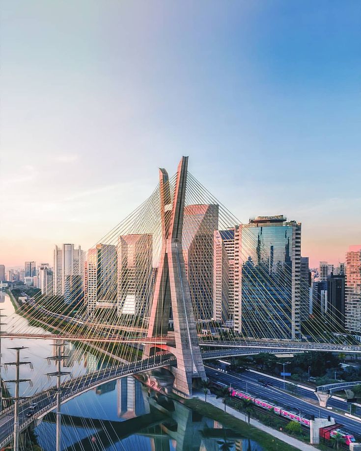 an aerial view of a bridge in the middle of a city with tall buildings on both sides