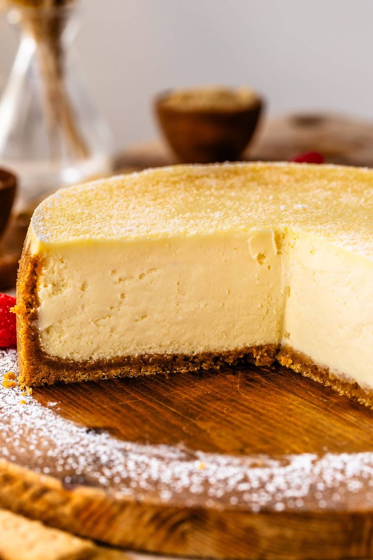 a cheesecake on a wooden platter with powdered sugar