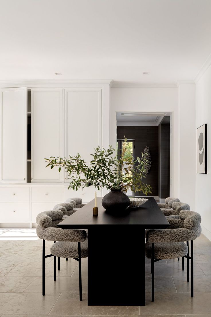 a dining room table with chairs around it and a vase filled with flowers on top