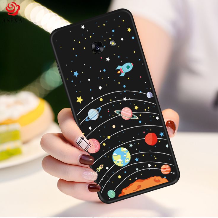 a woman holding up her phone case with planets and stars on it