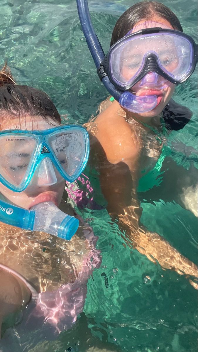 two children in the water with snorkels on their heads and goggles on