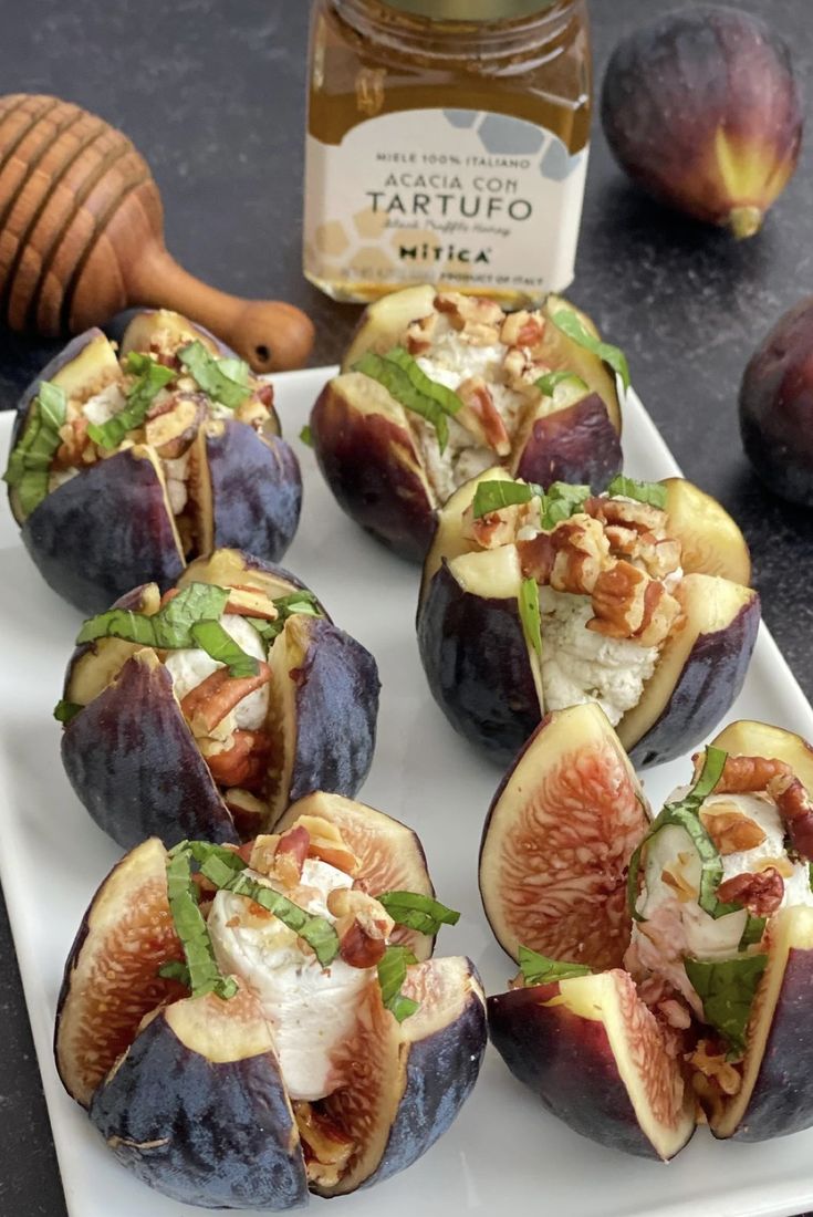 figs are arranged on a white plate next to honey