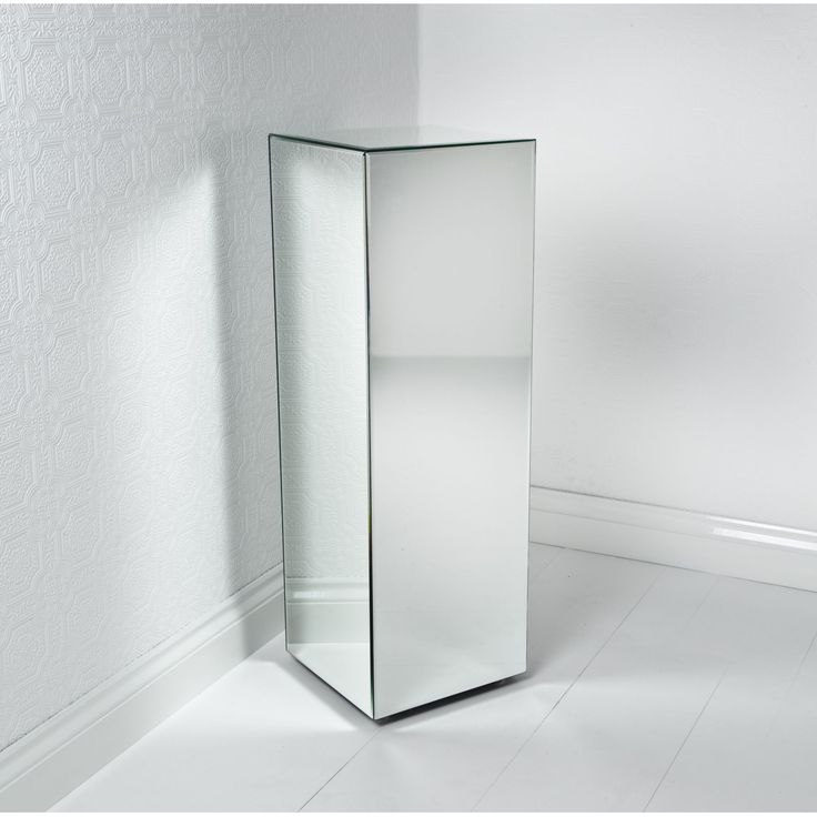 a tall mirrored cabinet in the corner of a room with white walls and flooring