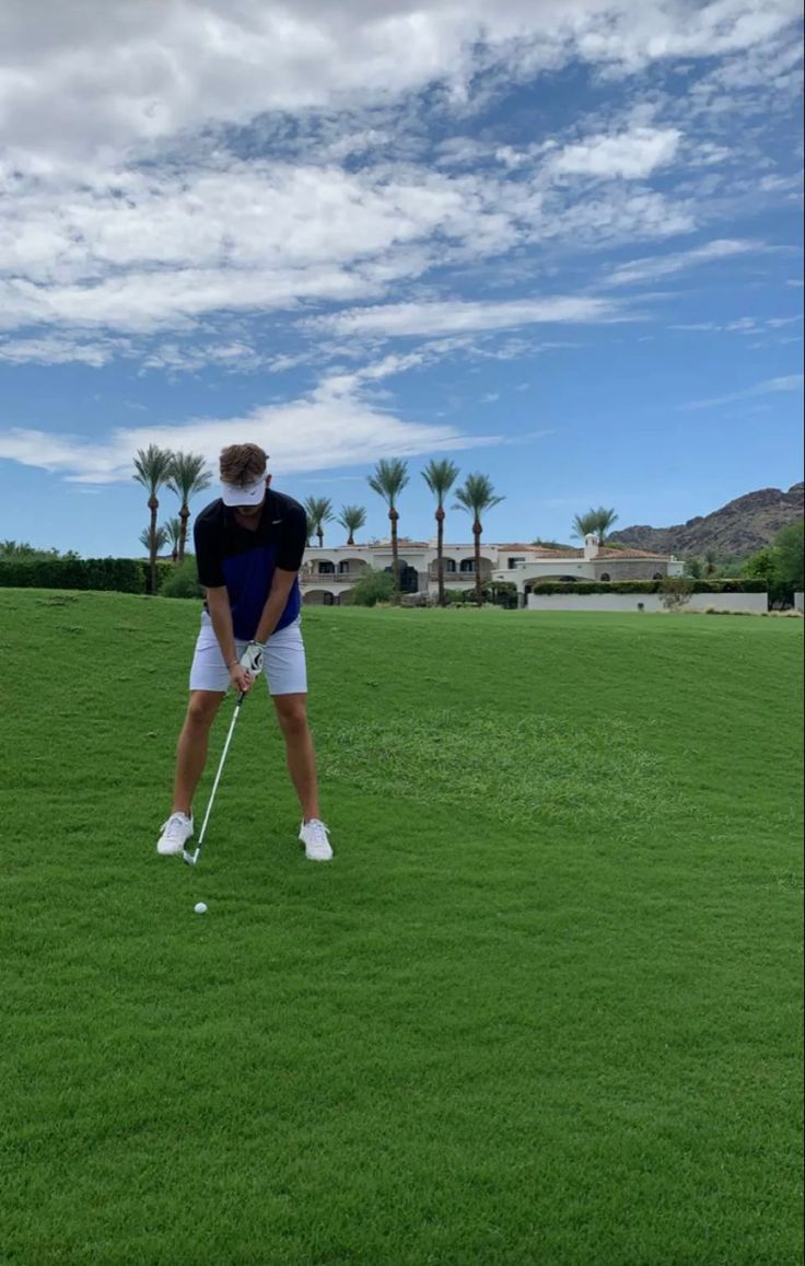 a man standing on top of a lush green field holding a golf racquet