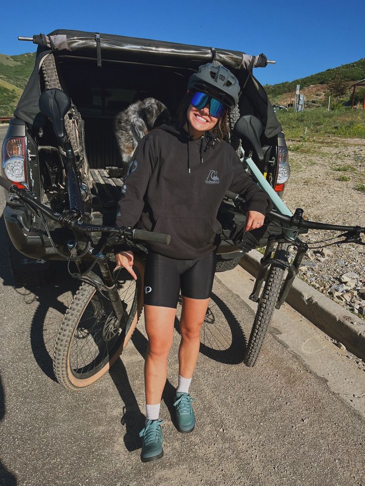 a woman standing next to her bike with the back of it's trunk open