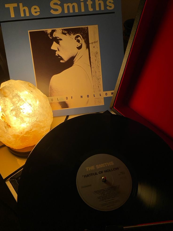 an old record player sitting on top of a table next to a light that is turned on