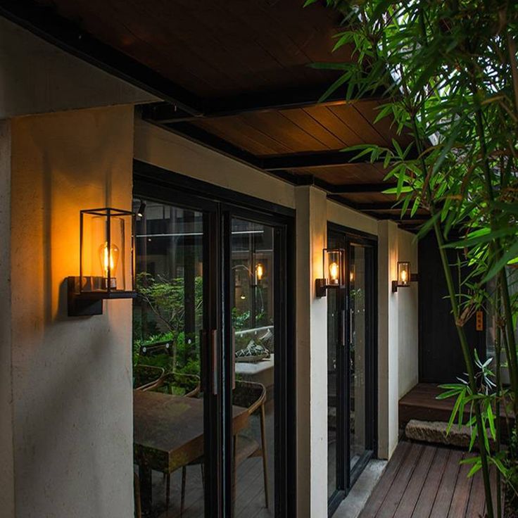 an outdoor patio with wooden flooring and plants on the side of it, surrounded by greenery