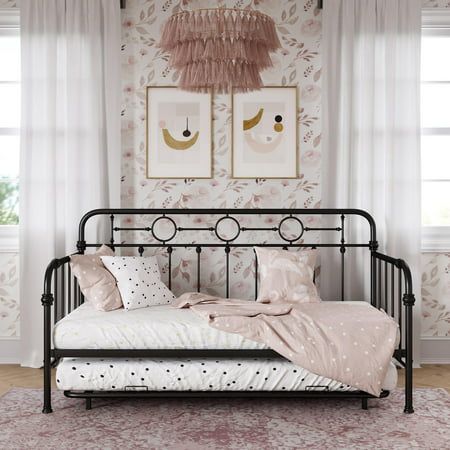 a black metal day bed with pink and white wallpaper in a girls bedroom area