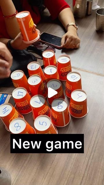 a group of people sitting around a table with orange cups on top of each other