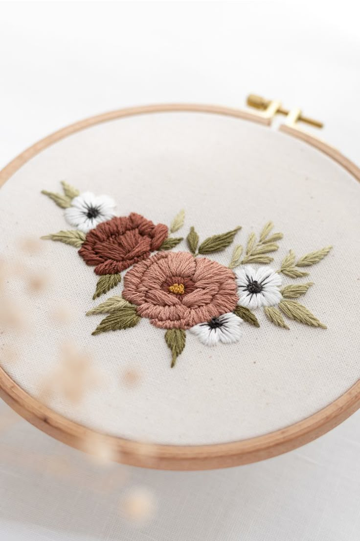 a close up of a embroidery on a wooden hoop with white and red flowers in it