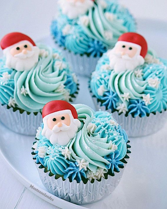 three cupcakes with frosting and santa clause on them sitting on a plate