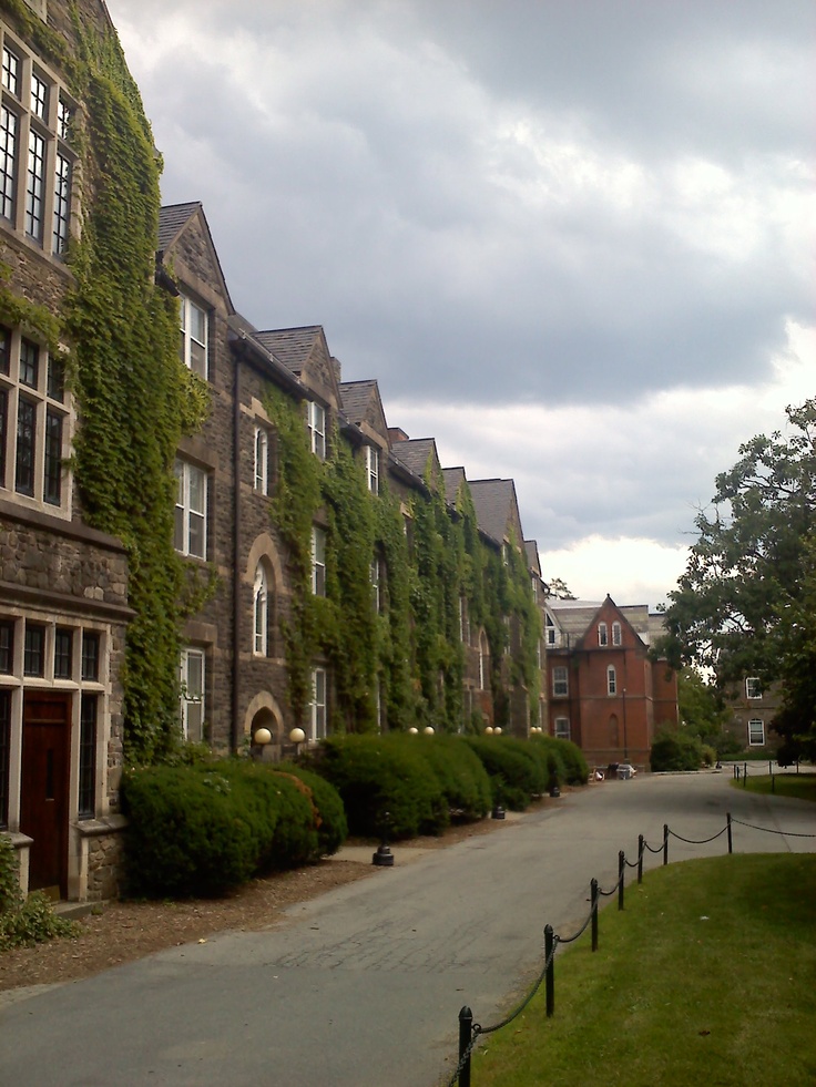 an old building with ivy growing on it's side and a paved road in front