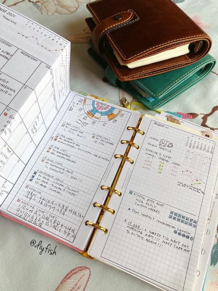 an open planner book sitting on top of a bed next to a notebook and pen