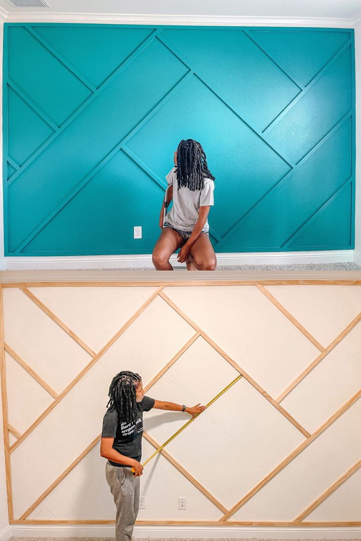 two people are standing in front of a blue wall and one is holding a measuring tape