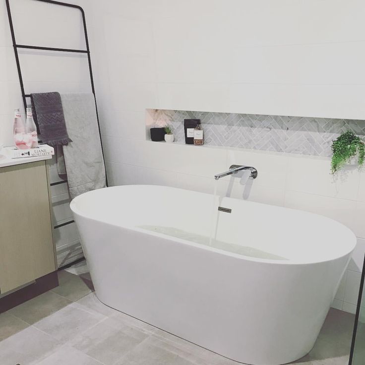 a white bath tub sitting inside of a bathroom next to a sink and shower head