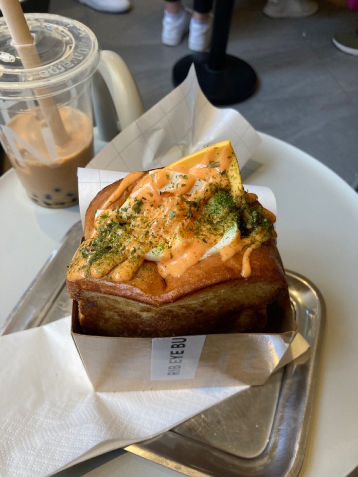 a piece of bread with sauce and cheese on it sitting on a plate next to a cup of coffee