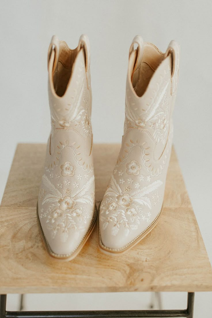 a pair of white boots sitting on top of a wooden table