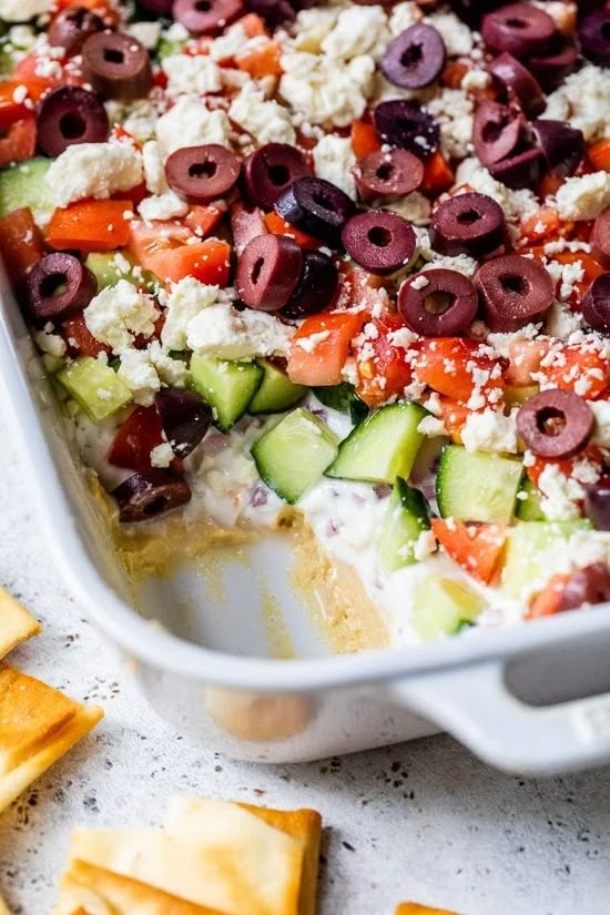 a casserole dish with olives, cucumber and feta cheese