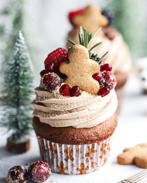 a cupcake with icing and berries on top is surrounded by cookies, cranberries, and christmas trees