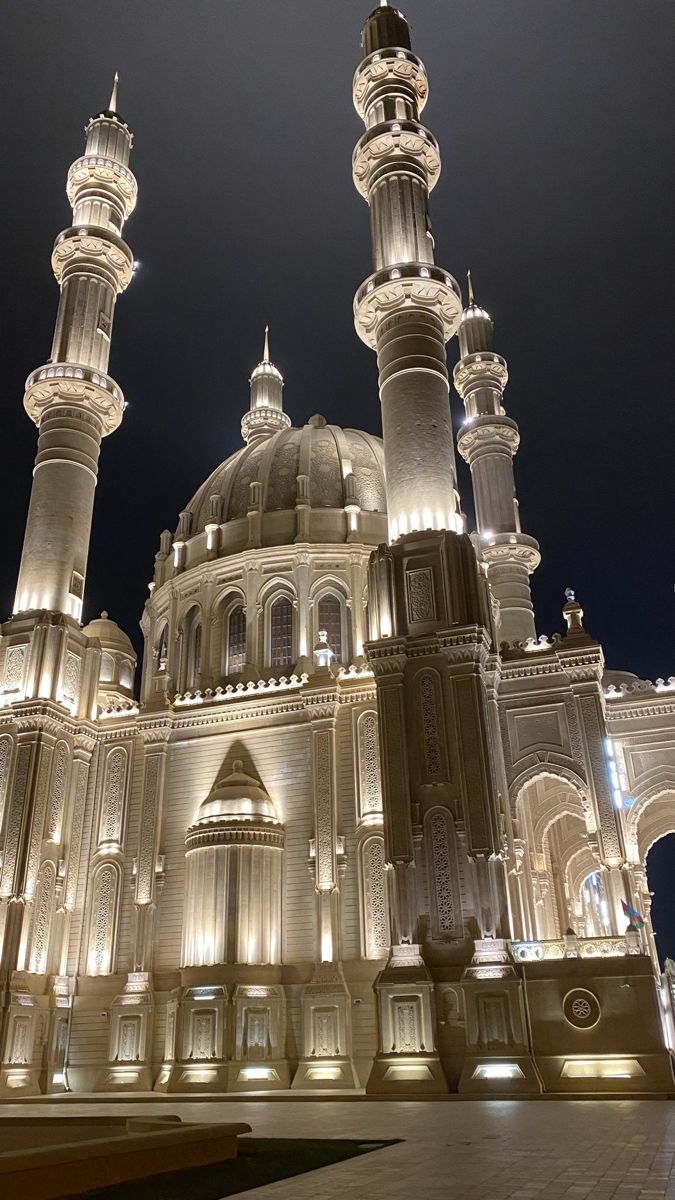 an ornate building lit up at night with lights on it's sides and pillars