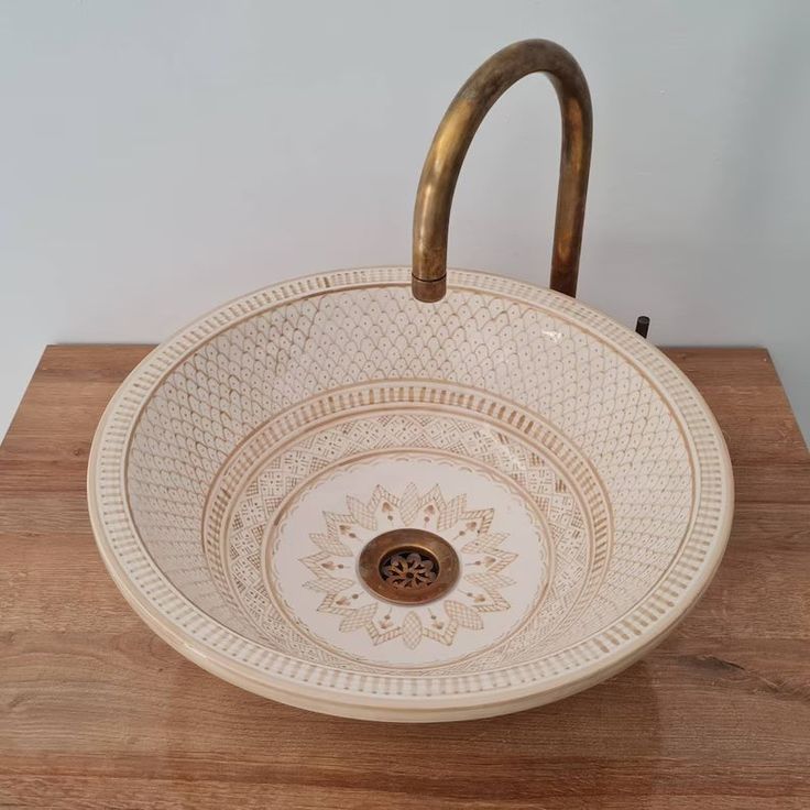 a white sink sitting on top of a wooden counter next to a wall mounted faucet