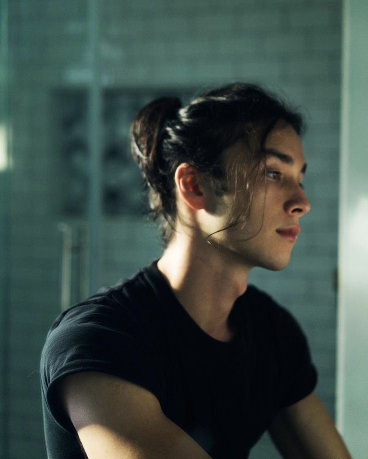 a woman is brushing her teeth in the bathroom with a mirror behind her and light shining on her face