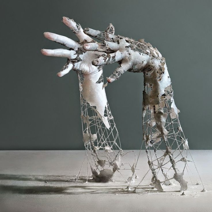 an artistic sculpture made out of white and black material with one hand reaching for the other