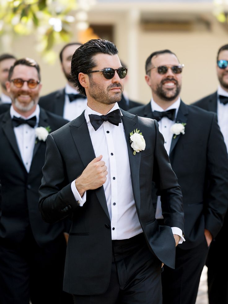 a group of men in tuxedos standing next to each other with sunglasses on