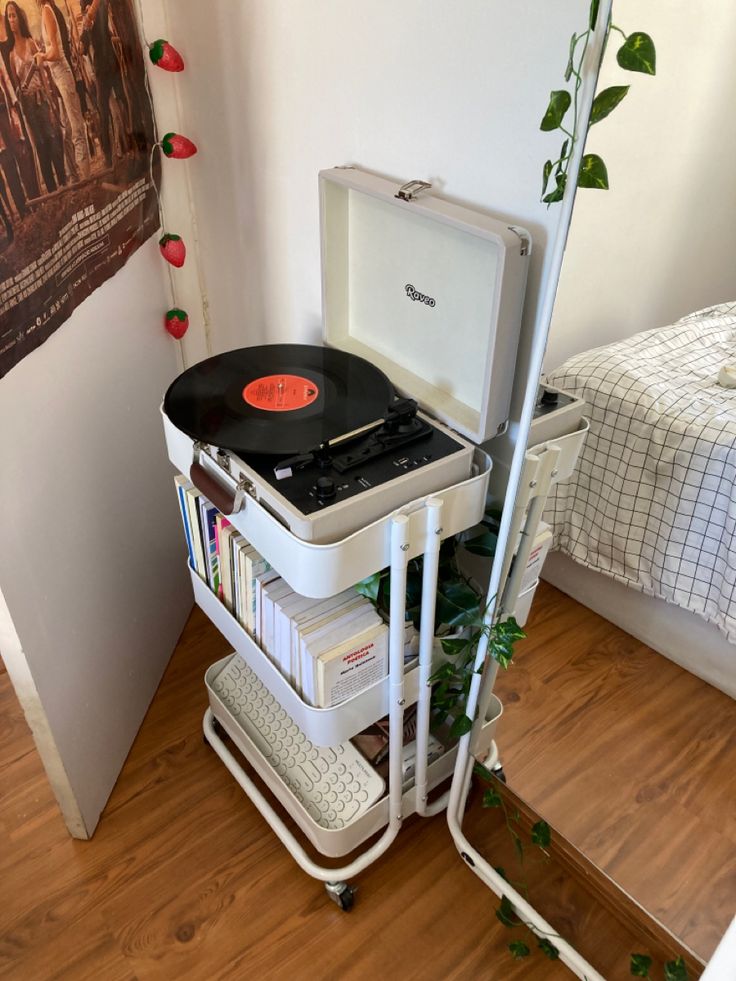 a record player sitting on top of a cart next to a bed