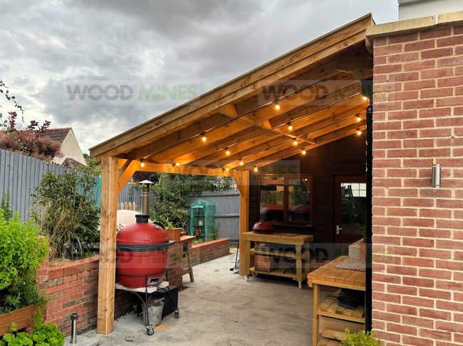 an outdoor bbq with lights on the roof and grilling area next to it