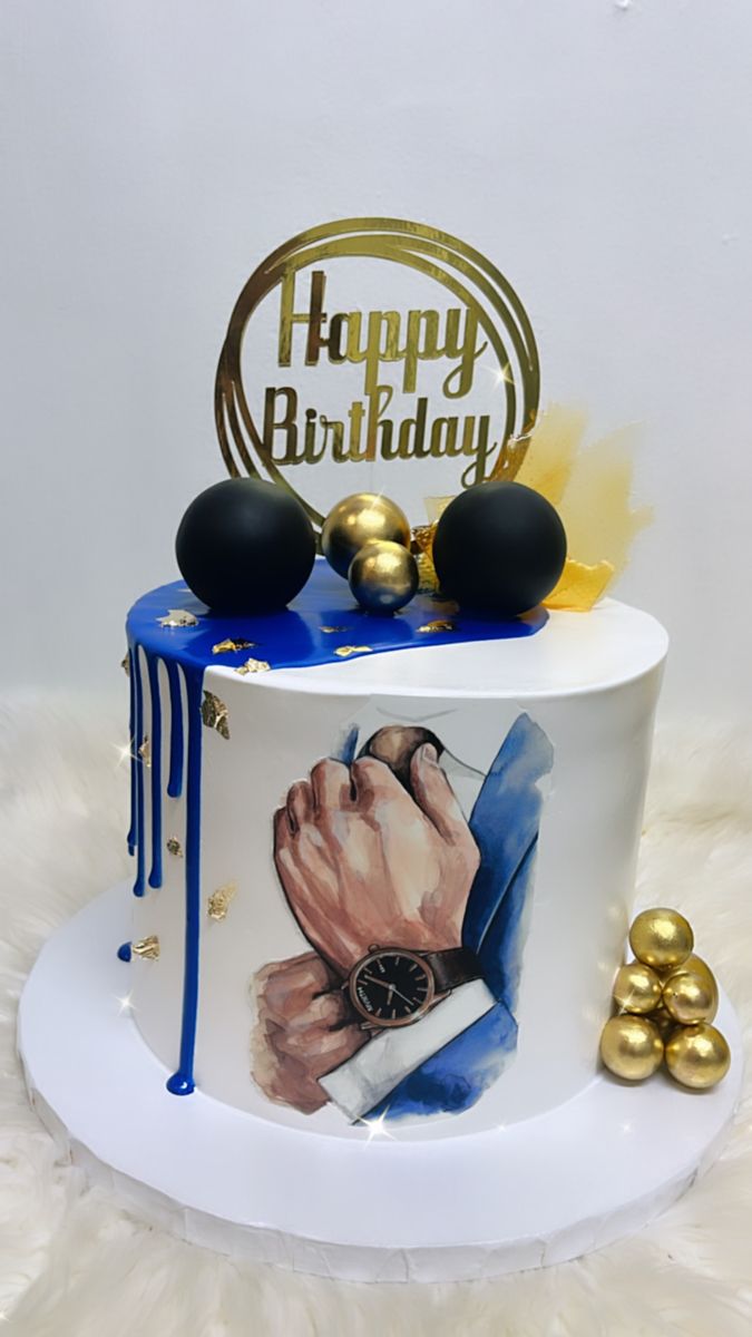 a birthday cake decorated with an image of a man's hand and gold balls