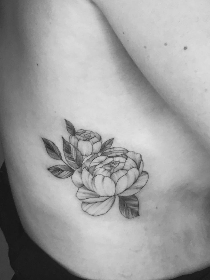 a black and white photo of a woman's stomach with a flower tattoo on it