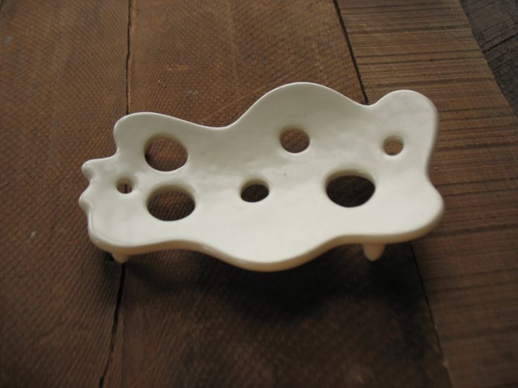 a white ceramic object sitting on top of a wooden table with holes in the middle