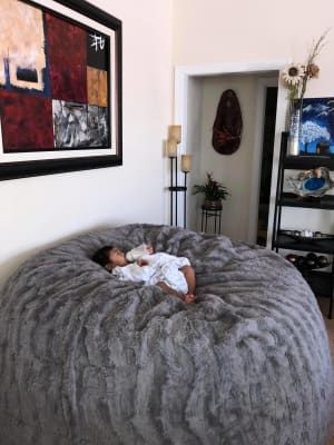 a baby is sleeping on a large bean bag chair in the middle of a living room