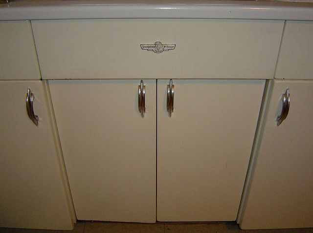 an old fashioned kitchen with white cabinets and silver knobs on the front door handles